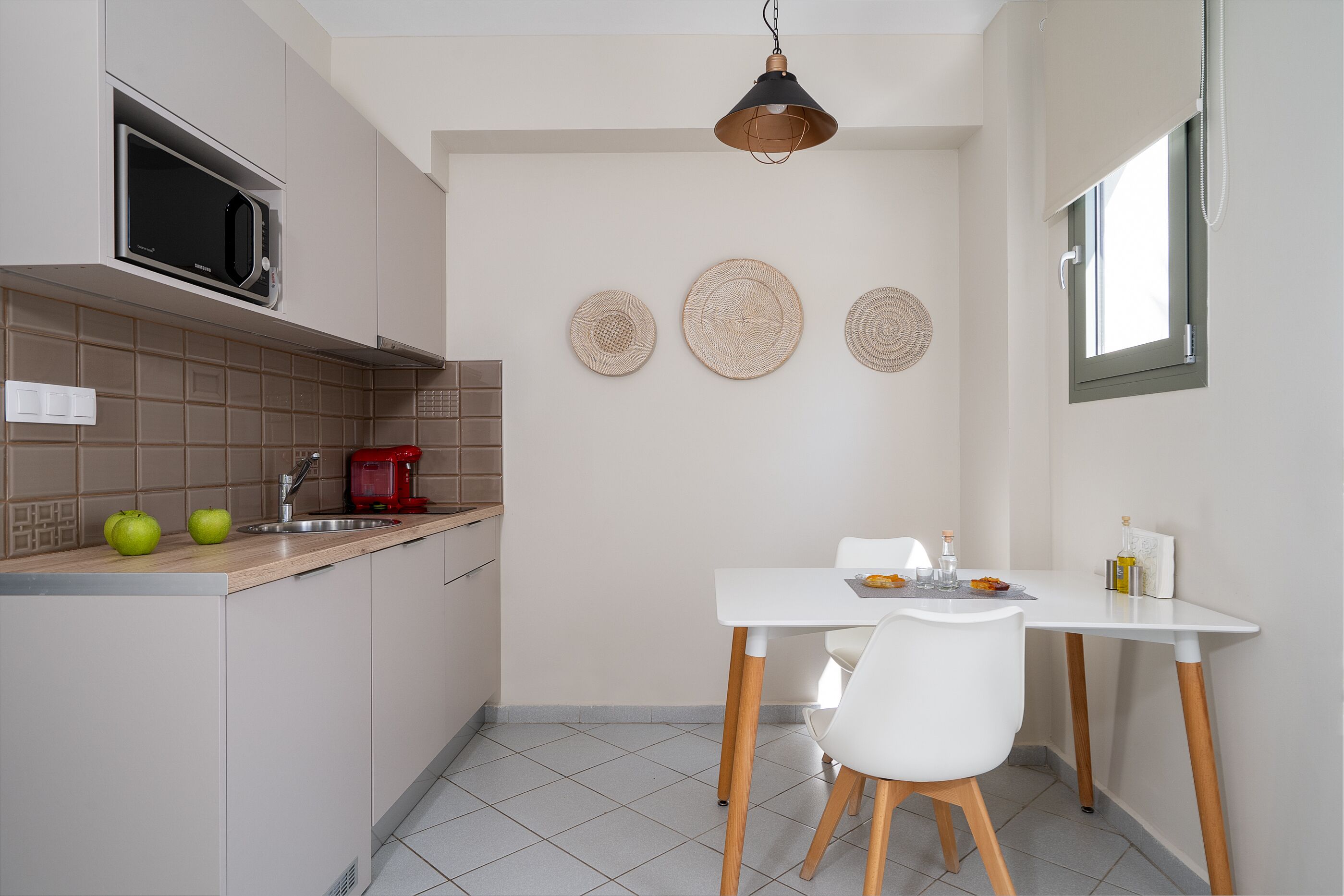 A compact kitchen with a microwave, sink, and a dining area with a white table and chairs.