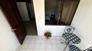 Zona de pati petita amb sòl de rajoles de disseny, una planta en test i una taula de metall amb caires.