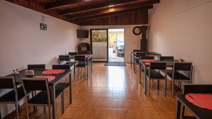 Zona de menjador amb bigues de sostre de fusta, un paviment de rajola i vista cap a l'exterior a través d'una porta de vidre.