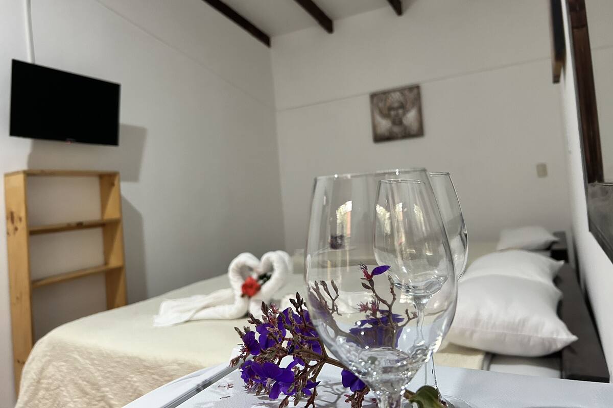 A bedroom with a bed, a wooden shelf, a flat-screen TV, and a wall-mounted picture.