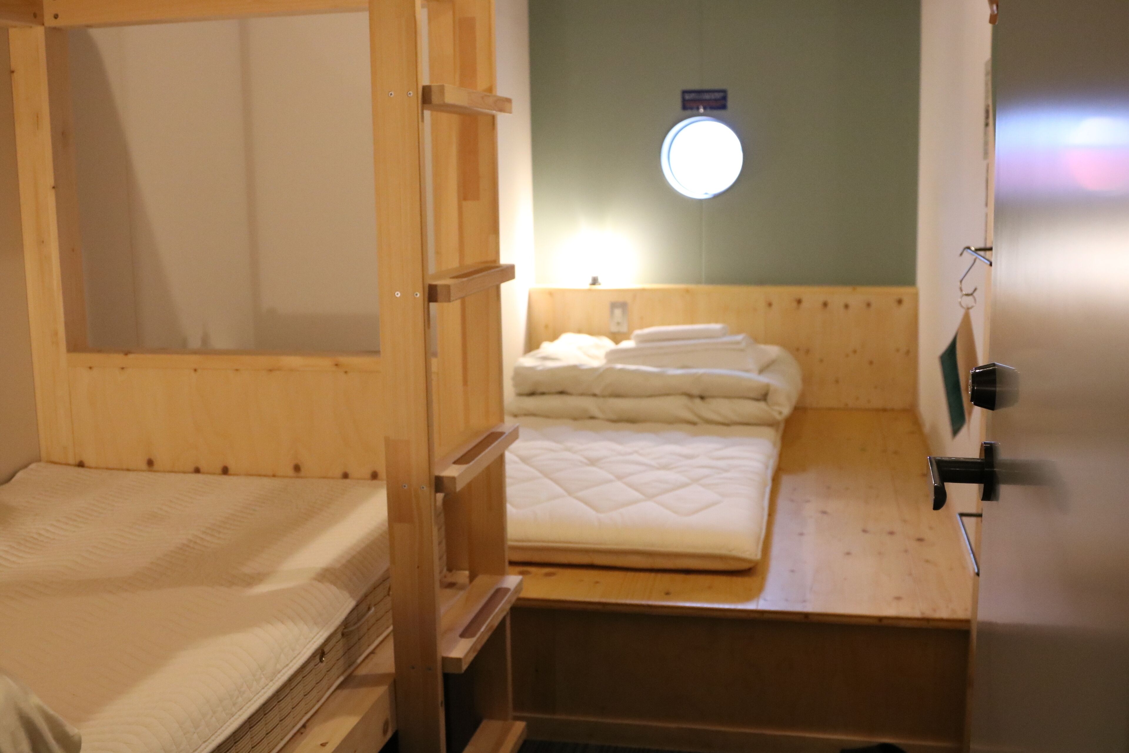 A bunk bed room with a wooden headboard, a bedside table, and a small shelf.