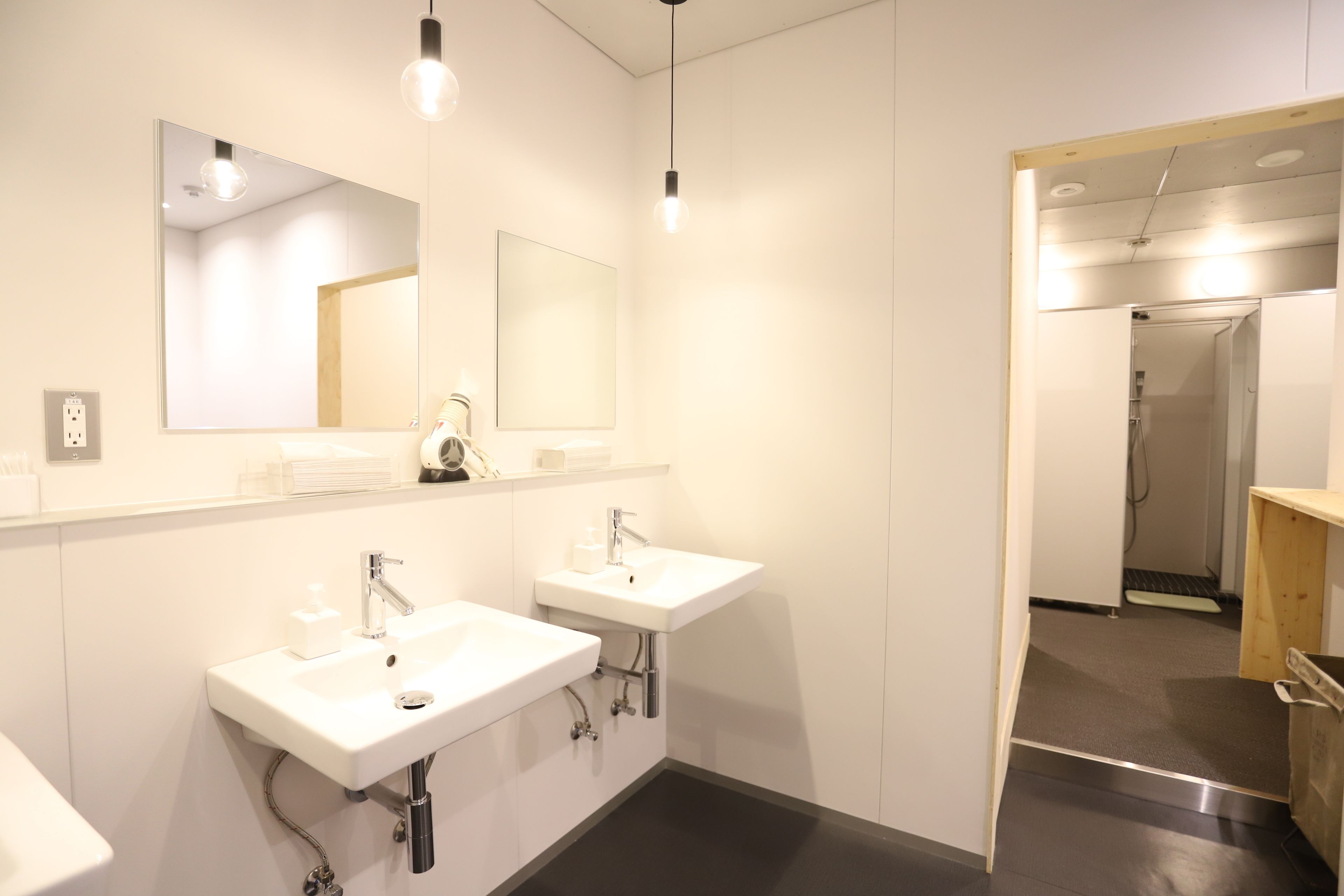A modern bathroom with two sinks, a large mirror, and a shower area.