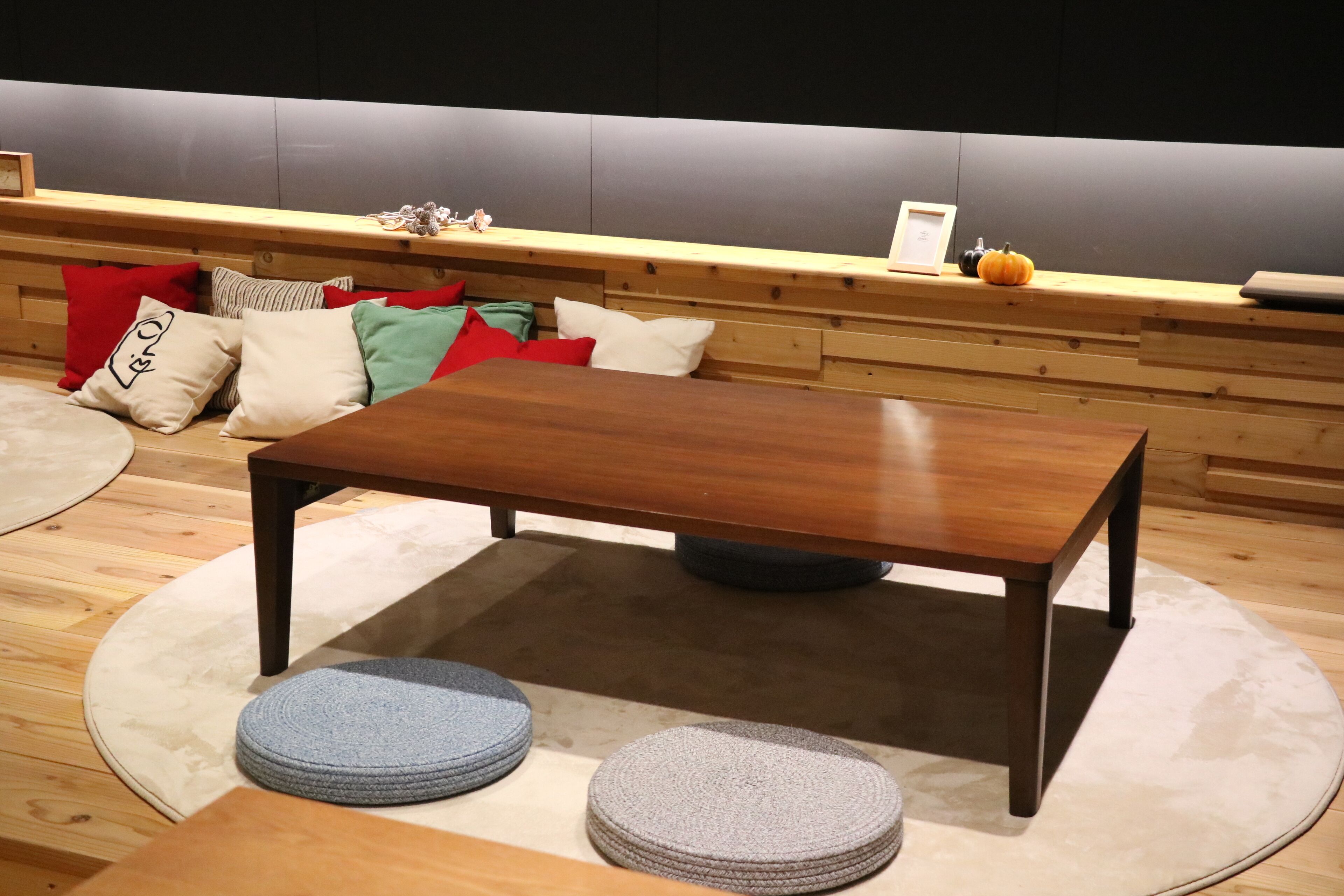 A wooden table with a round table runner and two round stools.