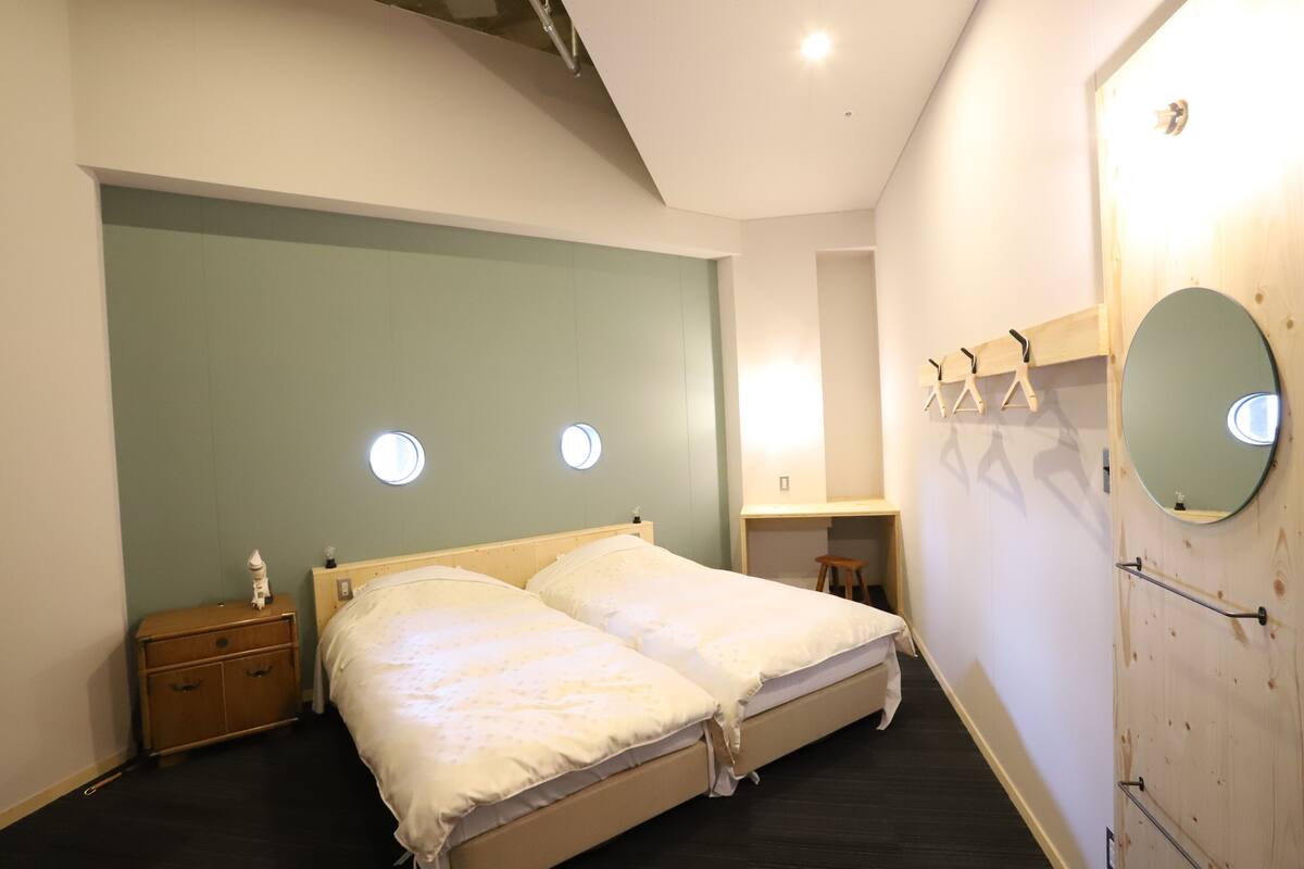 A bedroom with two beds, a dresser, a mirror, and a small stool.