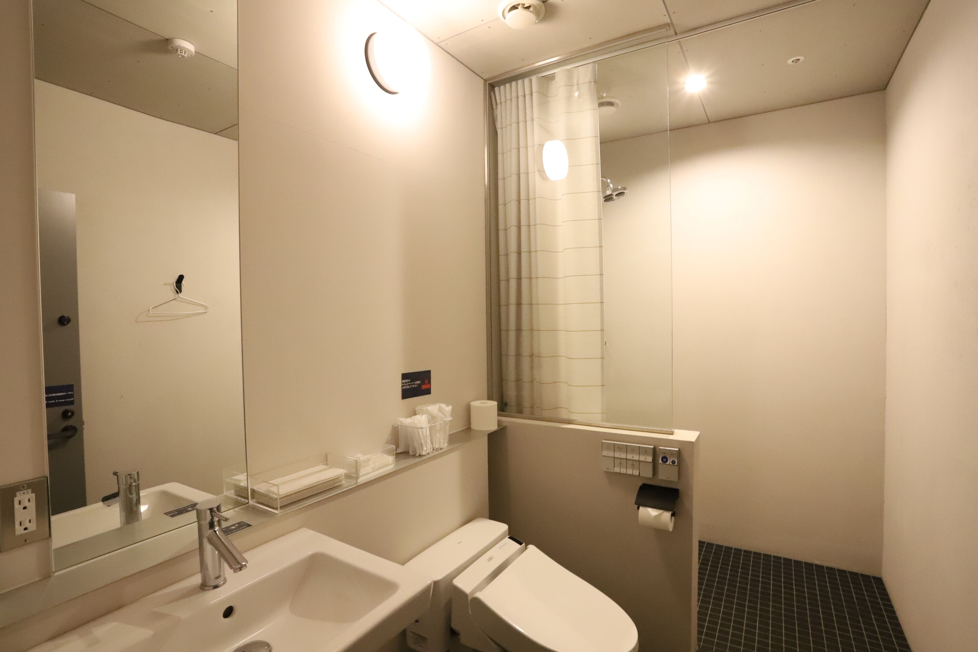 Een moderne badkamer met een wastafel, spiegel en douche.
