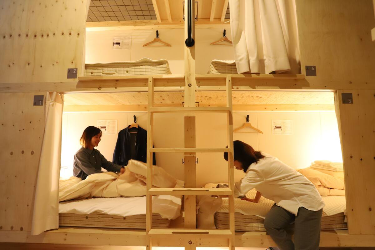 A bunk bed room with wooden frames, two beds, and a hanging clothes rack.