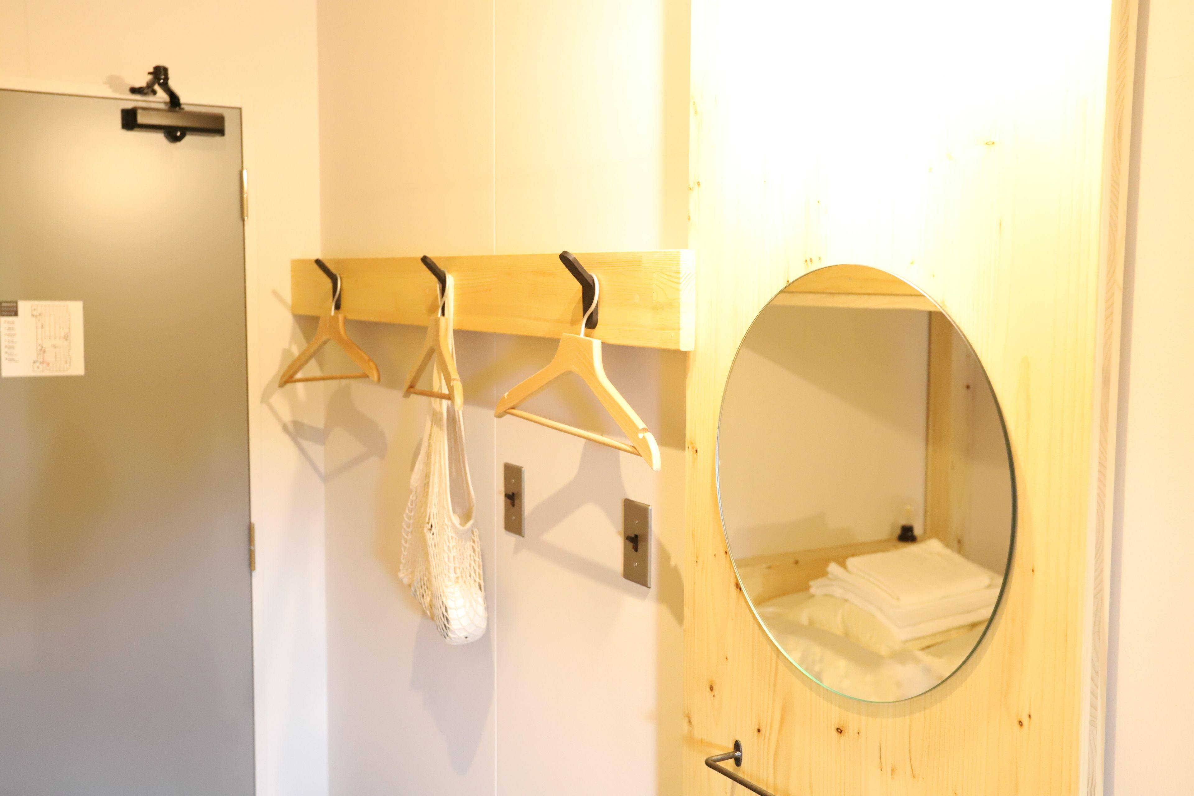 A bathroom with a wooden door, a mirror, and a towel rack with a white towel and a white bag hanging.