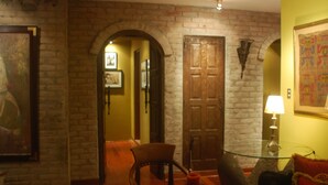 A room with a brick wall, wooden door, and a glass table with a lamp. - Black Shark Apartments (Lima)