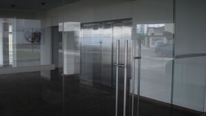 A modern building entrance with glass doors and a clear view of the outside. - Black Shark Apartments (Lima)