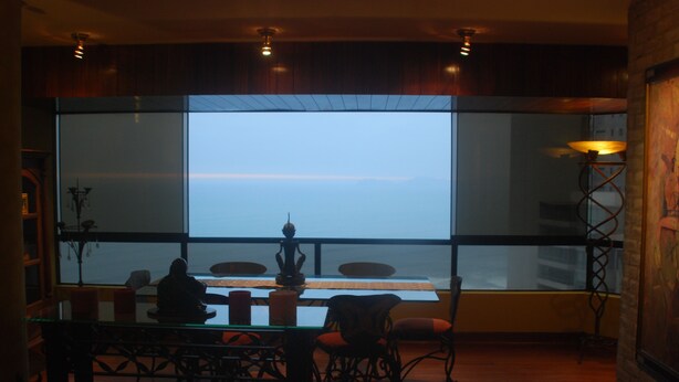 A dining area with a large window, a table with chairs, and a decorative lamp. - Black Shark Apartments (Lima)