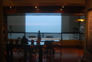 A dining area with a large window, a table with chairs, and a decorative lamp. - Black Shark Apartments (Lima)
