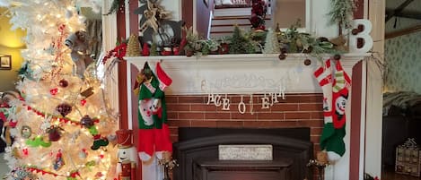 Une cheminée décorée avec des chaussettes de Noël, un sapin de Noël et une inscription au-dessus de la cheminée.