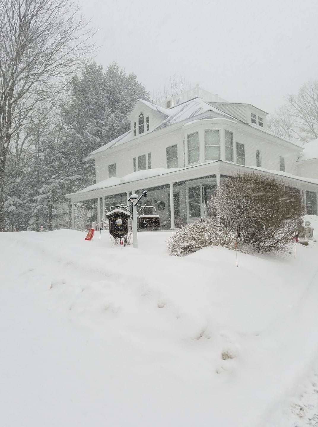 Un'ampia casa a due piani con un portico coperto e un paesaggio innevato.