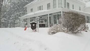 Un'ampia casa a due piani con un portico coperto e un paesaggio innevato.