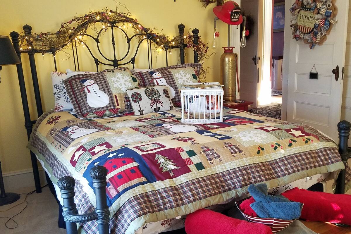 Una cama con colcha adornada con diversos diseños y un cabecero decorado con luces y guirnaldas.