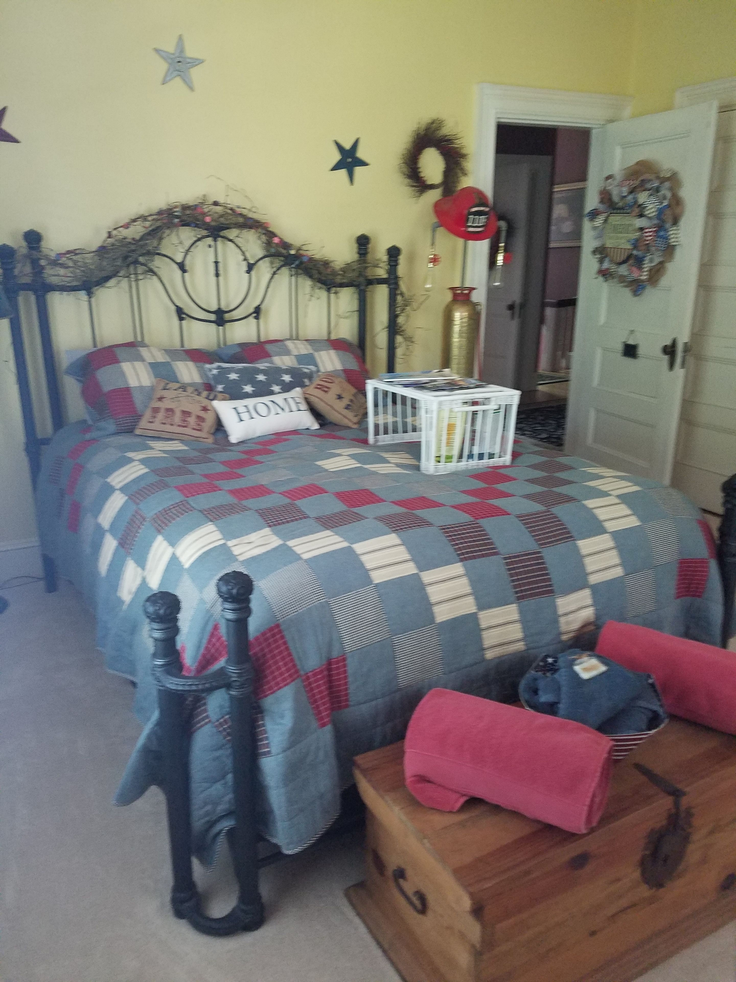 A bedroom with a bed, a wooden chest, and a wall with decorative items.