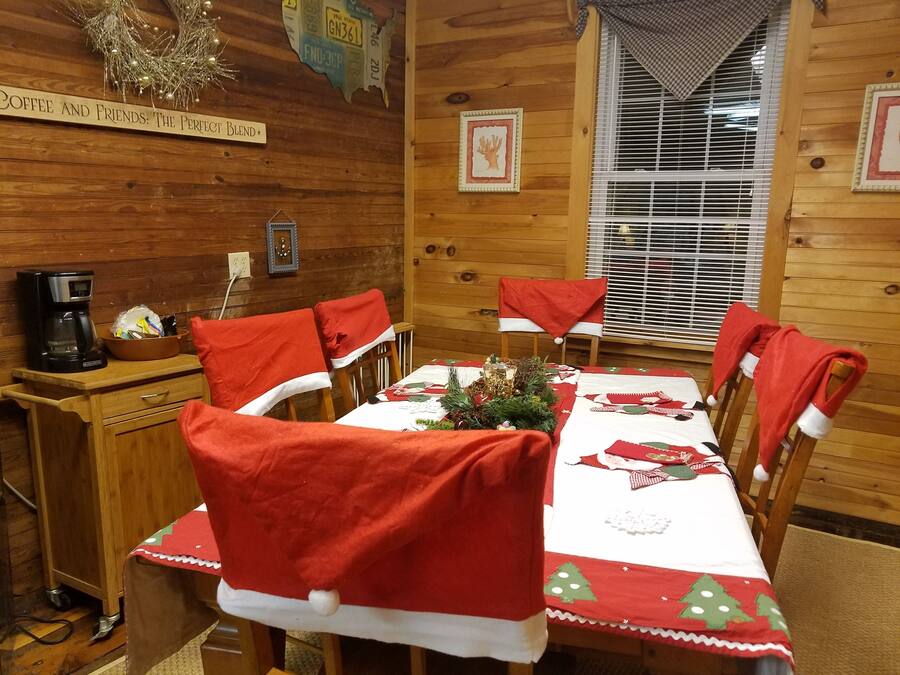 Una habitació d'estil cabana acollidora, amb interior de fusta, una taula de dinar coberta amb teles de taula vermelles i blanques i decoracions de Nadal.