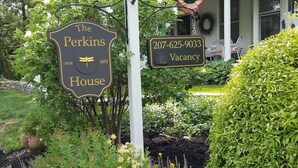 Ein Haus mit einem Schild, auf dem 'The Perkins House' steht, und einem 'Freie Zimmer' Schild mit einer Telefonnummer.