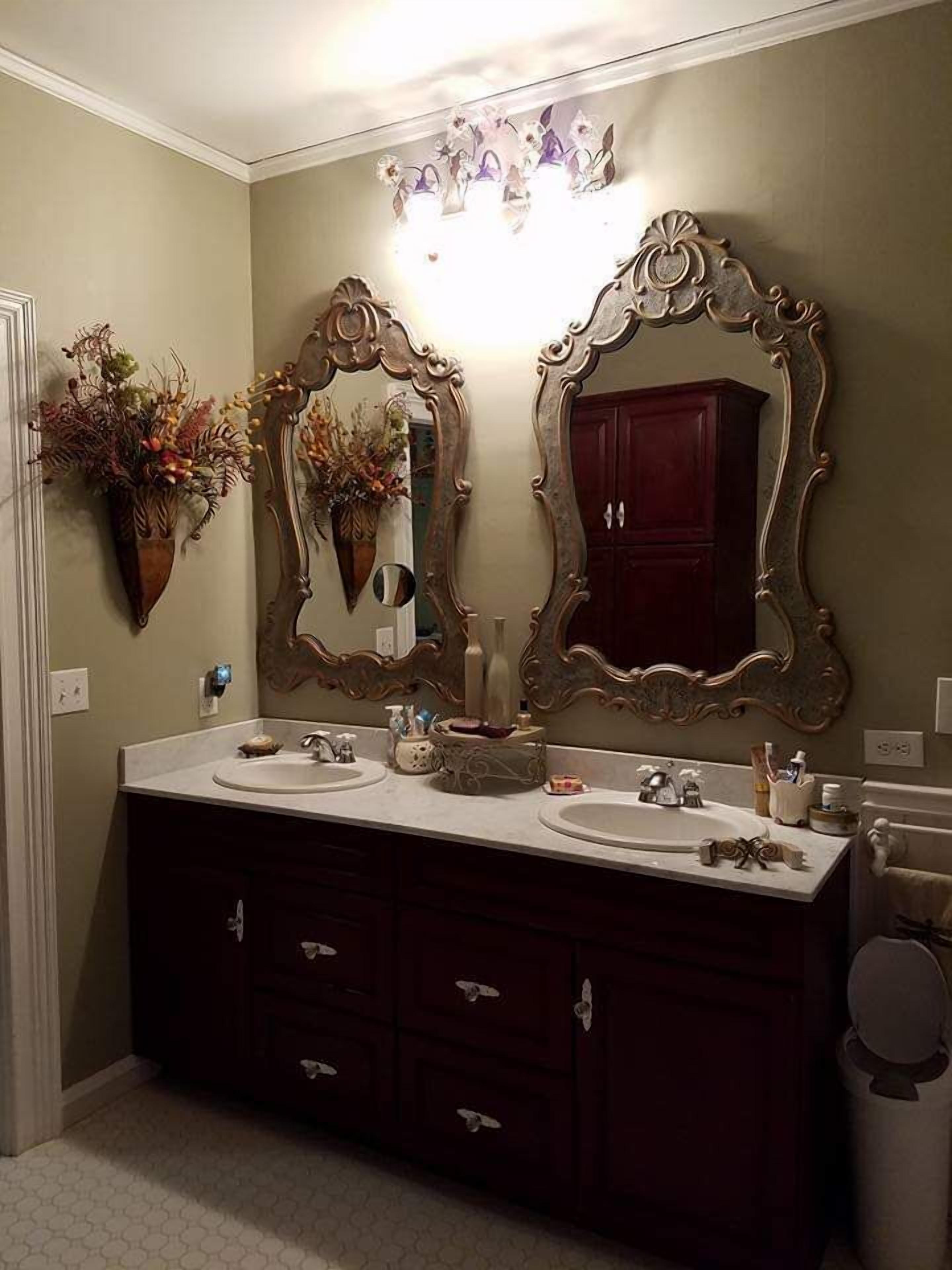 A bathroom with two sinks, dark wooden cabinets, and large ornate mirrors.