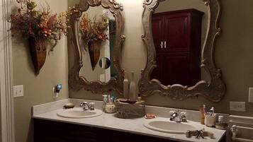 A bathroom with two sinks, dark wooden cabinets, and large ornate mirrors.