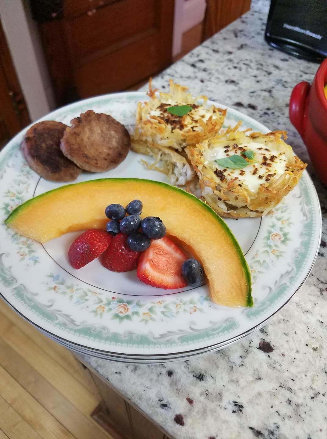 A plate with a slice of cantaloupe, strawberries, and blueberries.