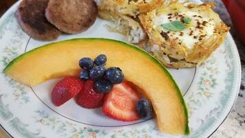 A plate with a slice of cantaloupe, strawberries, and blueberries.