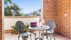 A small patio area with two ornate metal chairs and a round table, a bottle of champagne, and a box of chocolates. - Adelaide Style Accommodation - CLOSE TO CITY - 3Bdrm - In elite North Adelaide (North Adelaide)