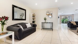 A modern living room with a dark grey sofa, a white coffee table, and a black console table with decorative mirrors. - Adelaide Style Accommodation - CLOSE TO CITY - 3Bdrm - In elite North Adelaide (North Adelaide)
