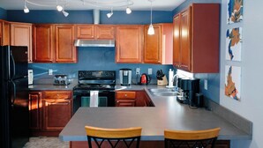 Una cocina con armarios de madera, un refrigerador negro, una estufa y una cafetera.
