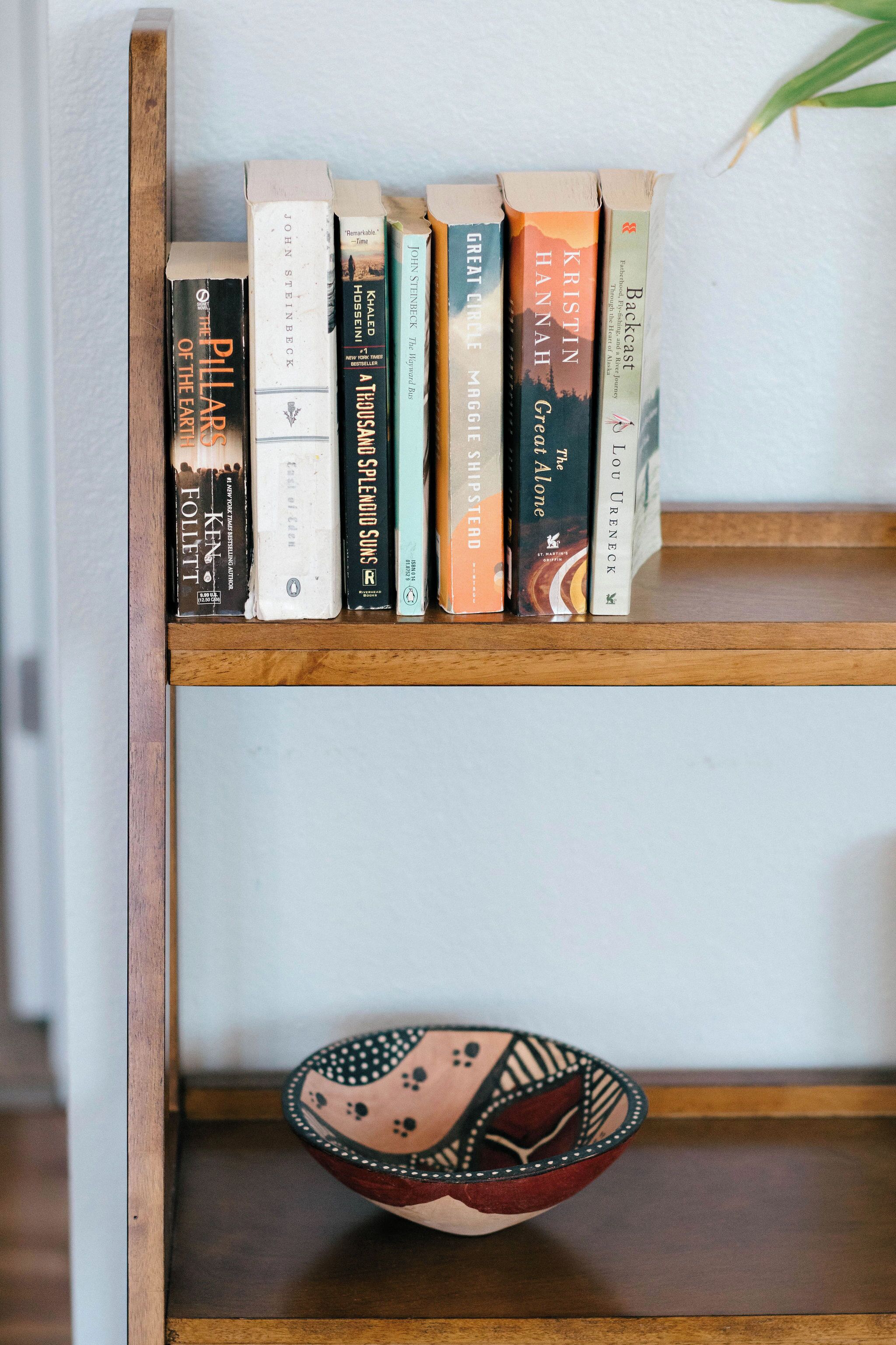 Ein Bücherregal aus Holz mit Büchern und einer dekorativen Schale.