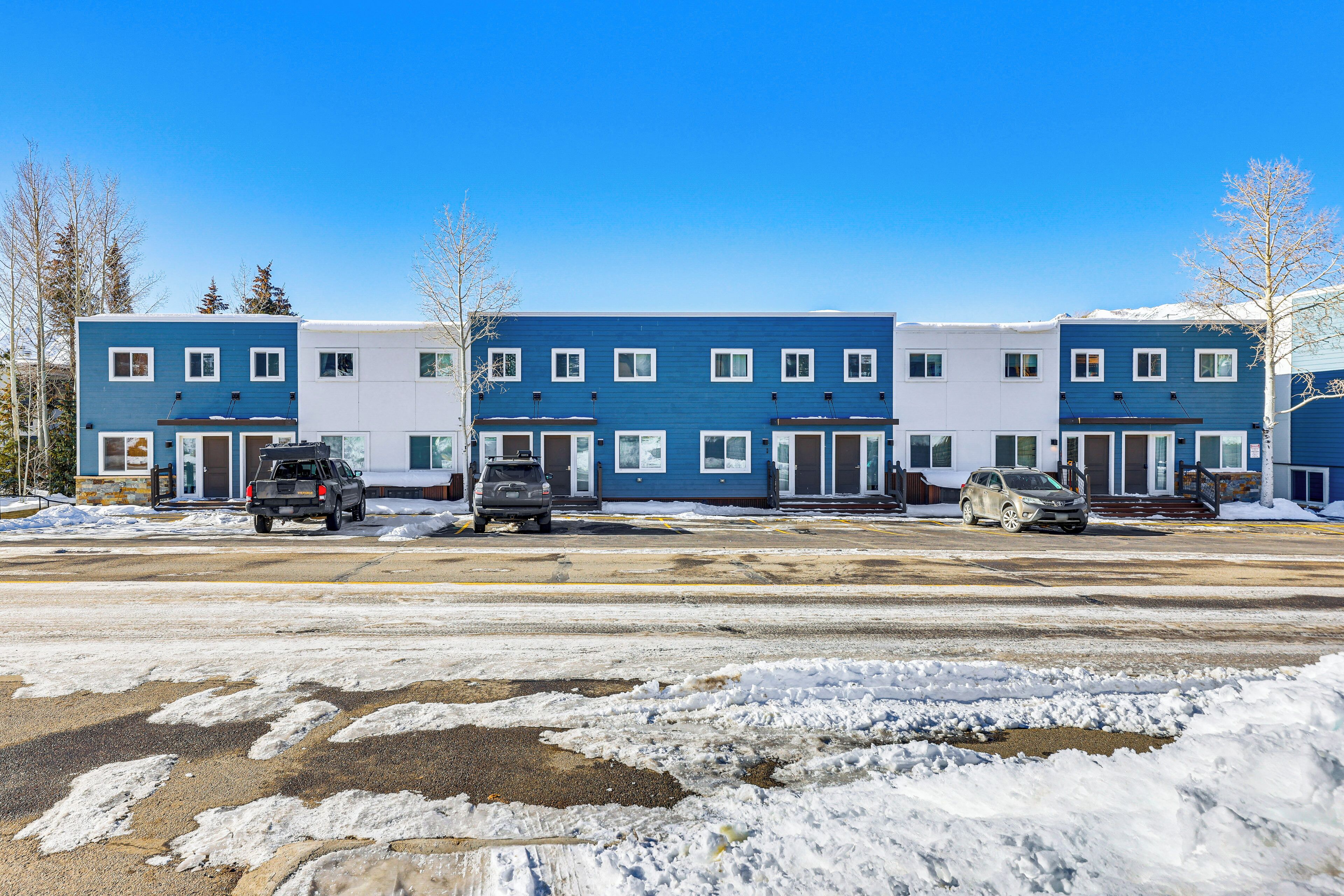 A row of blue and white buildings with multiple parking spaces in front.