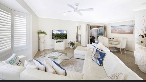Un salon moderne avec un canapé blanc, une table basse en verre et un ventilateur de plafond.