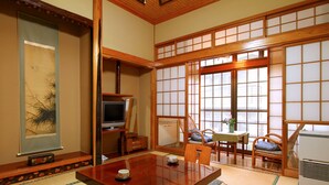 A traditional Japanese room with tatami flooring, a low wooden table, a television, and sliding doors. - Mogamiya Ryokan (Shiroishi)