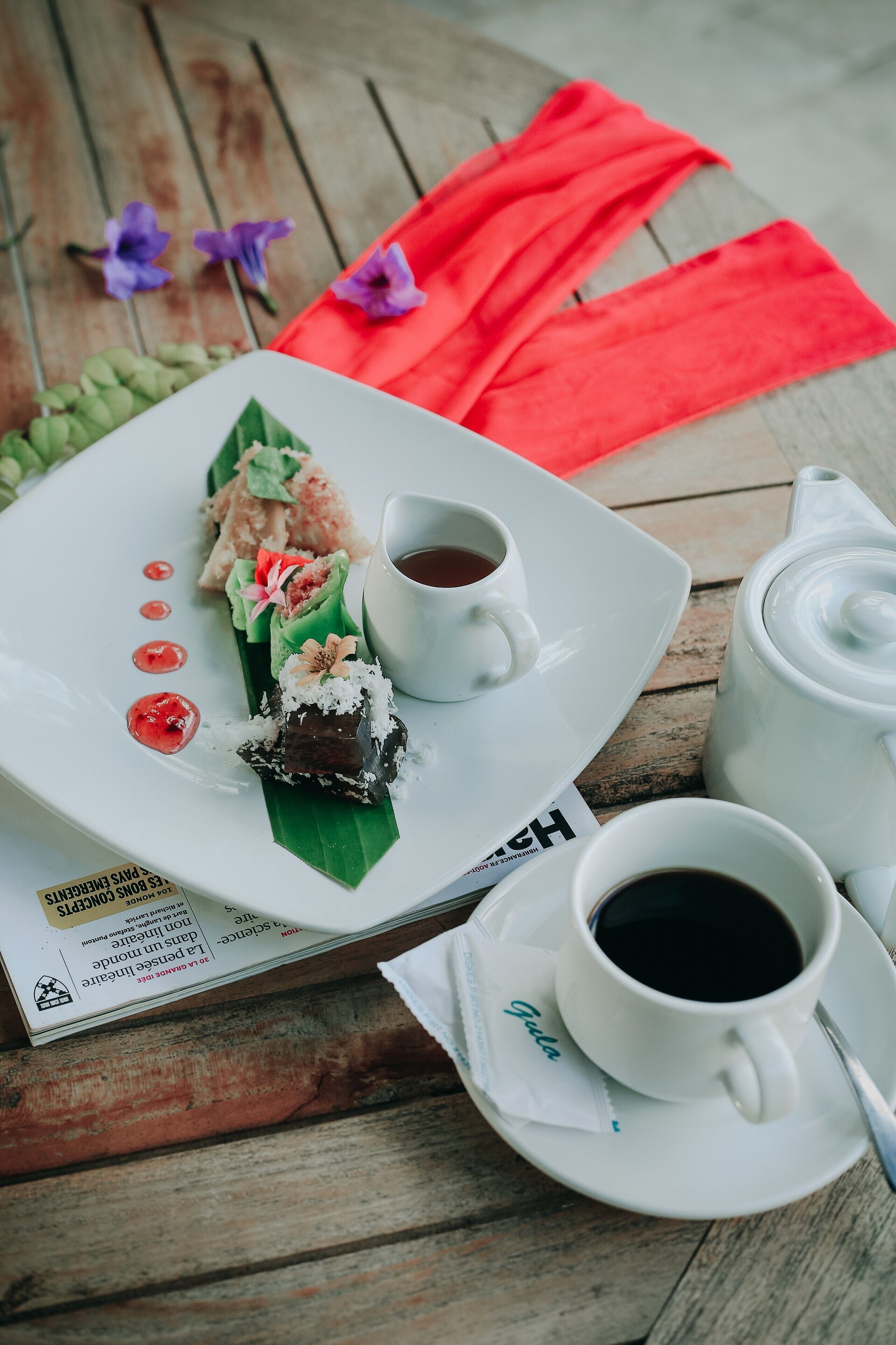 A table with a plate of food, two cups of coffee, and a teapot.