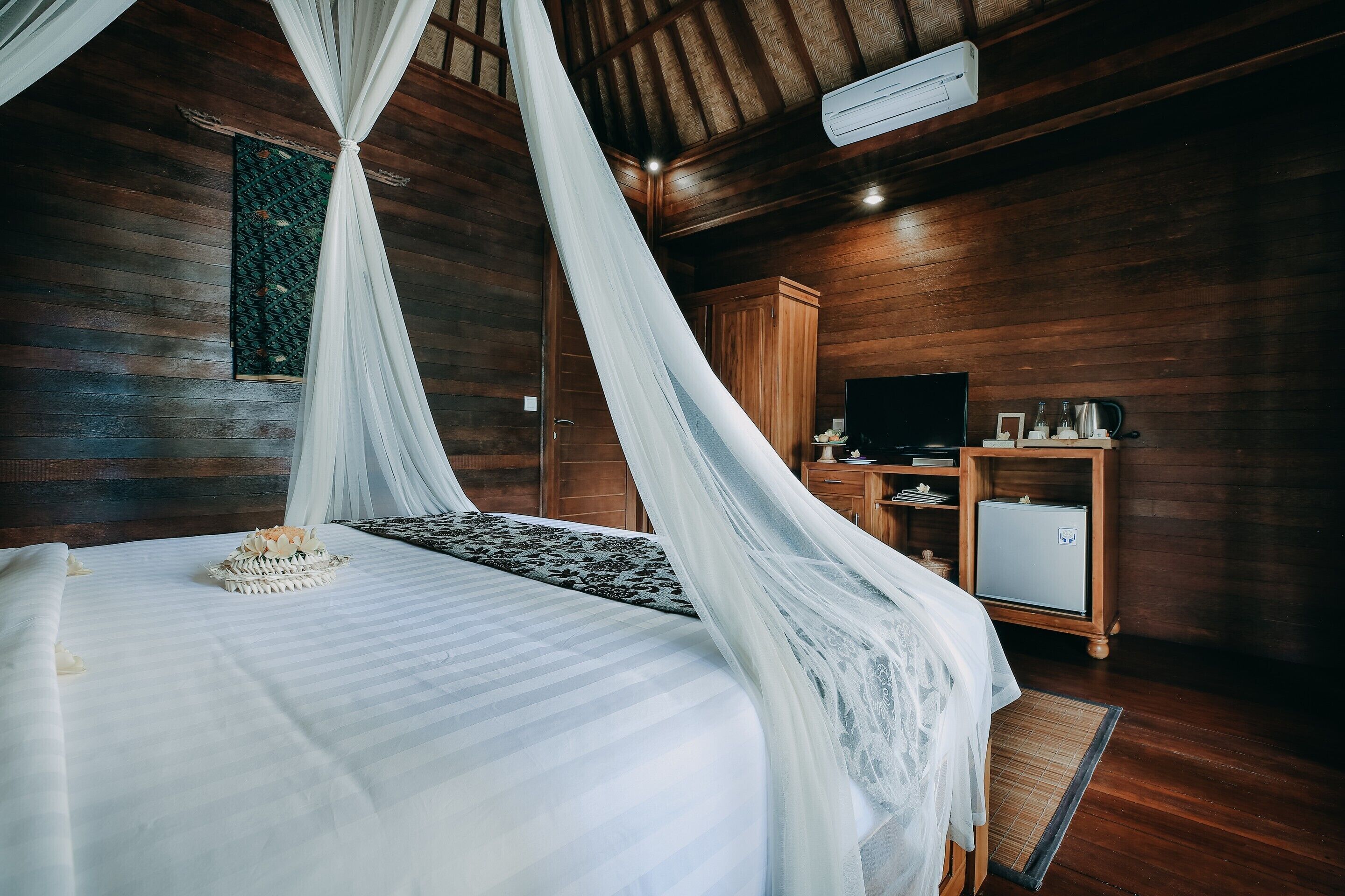 A bedroom with a bed, a television, a cabinet, and a wall-mounted air conditioner.