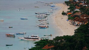 Una playa con numerosos barcos amarrados a la orilla y una hilera de casas con techos rojos.