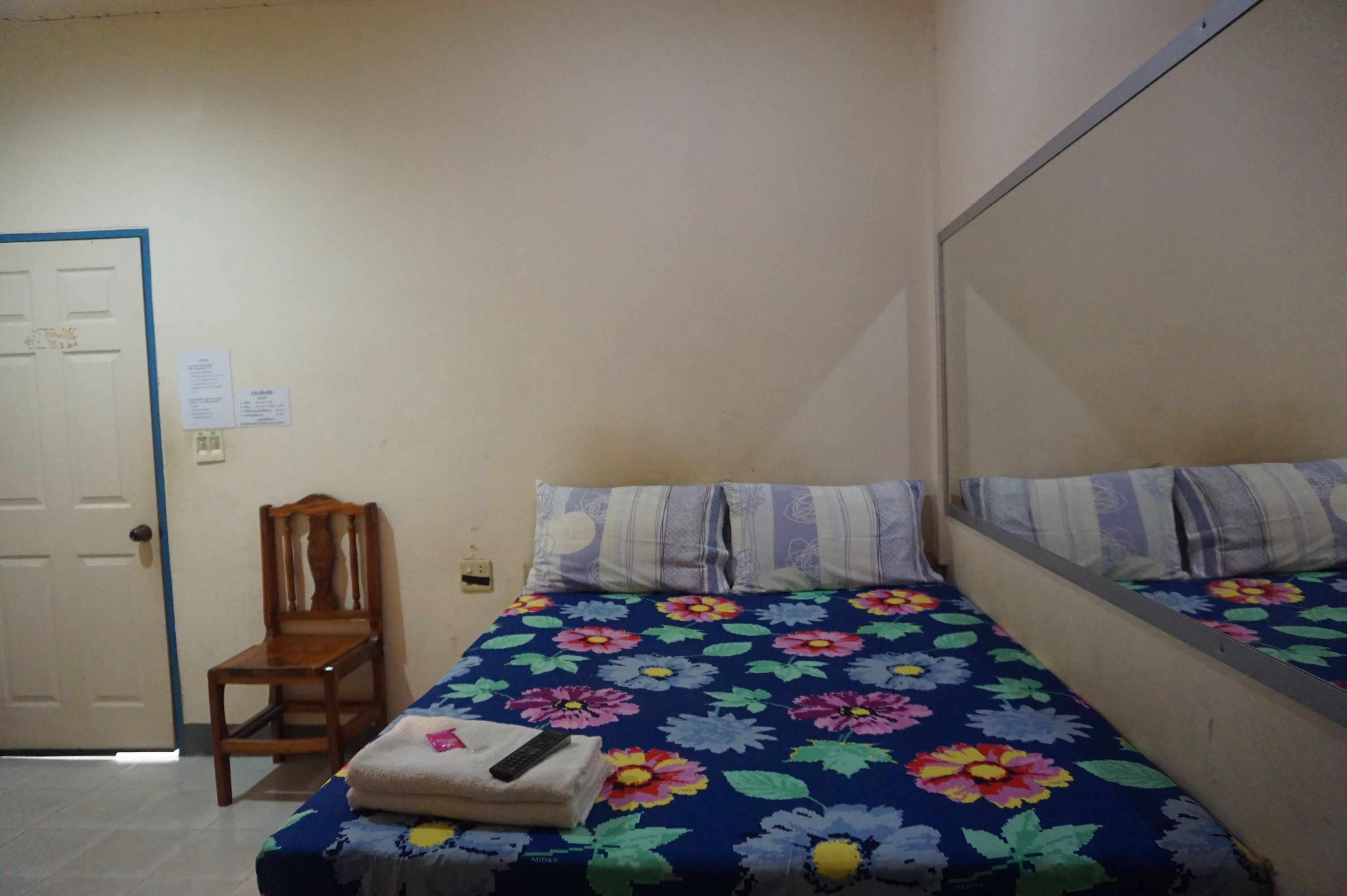 A small, simple room with a bed, a chair, and a door.