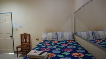 A small, simple room with a bed, a chair, and a door.