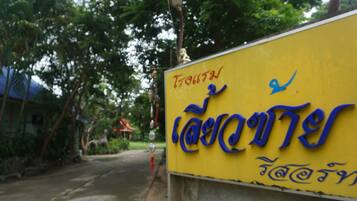 Located near a building, this sign marks a location amidst lush surroundings.