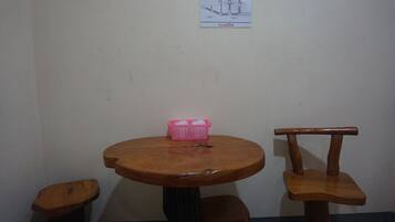 A small wooden table with a pink basket on it, two wooden chairs, and a wall-mounted sign.