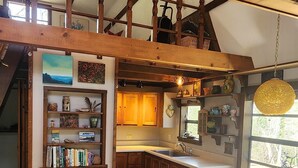 A spacious kitchen with wooden beams, a dining area, and a built-in bookshelf.