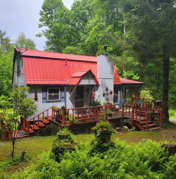Eine rustikale Holzhütte mit rotem Dach, einer Holzdiele und einer Treppe, die zum Eingang führt.