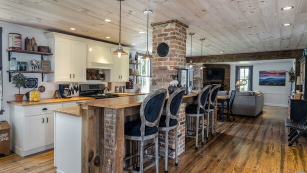 A spacious kitchen with a central island, wooden bar stools, and a brick fireplace. - Historical Property, Mountain View’s quiet country life. (Stanley)