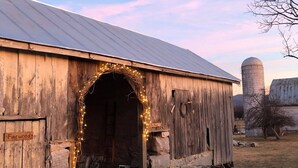 A rustic barn with a wooden door, a sign reading "Firewood", and a small porch area with chairs. - Historical Property, Mountain View’s quiet country life. (Stanley)