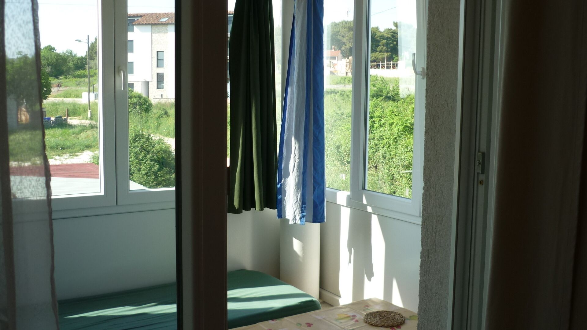 Ein Zimmer mit einem Bett, einem kleinen Tisch und Blick auf Grünflächen und Gebäude.