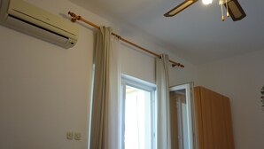 A room with a ceiling fan, an air conditioning unit, a window with curtains, and a wooden wardrobe. - Apartment Studio A2_Croatia, Istria, Medulin (Medulin)
