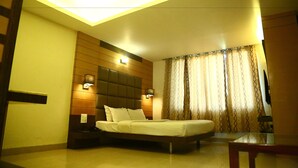 A modern bedroom with a bed, nightstands, and a ceiling light fixture. - Castle Inn (Khandwa)