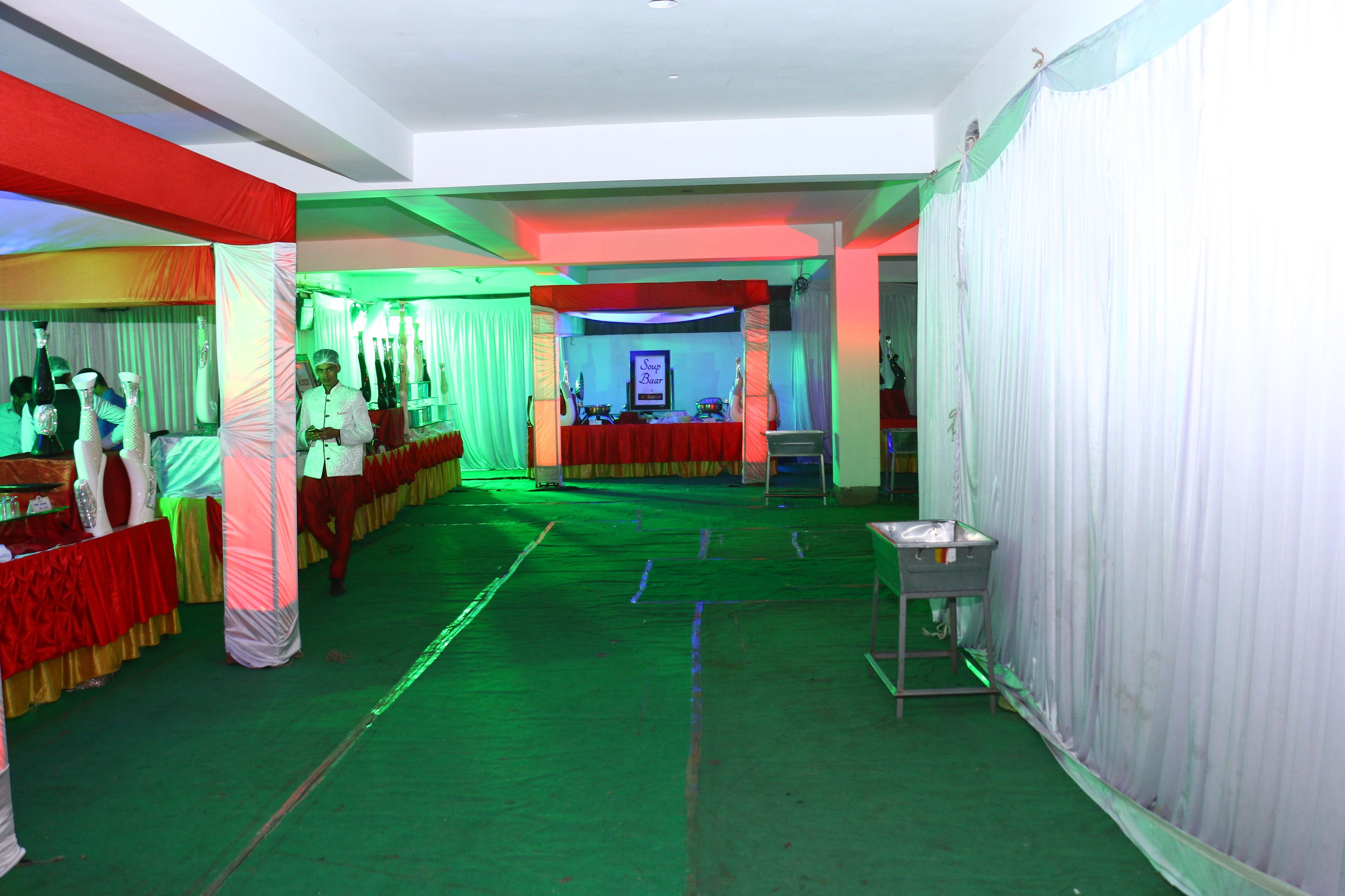 A room with a green carpet, white curtains, and a stage with a red backdrop.