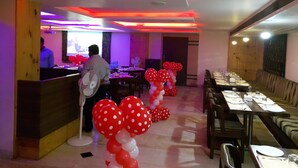 A restaurant with a long dining table, chairs, and a counter. - Castle Inn (Khandwa)