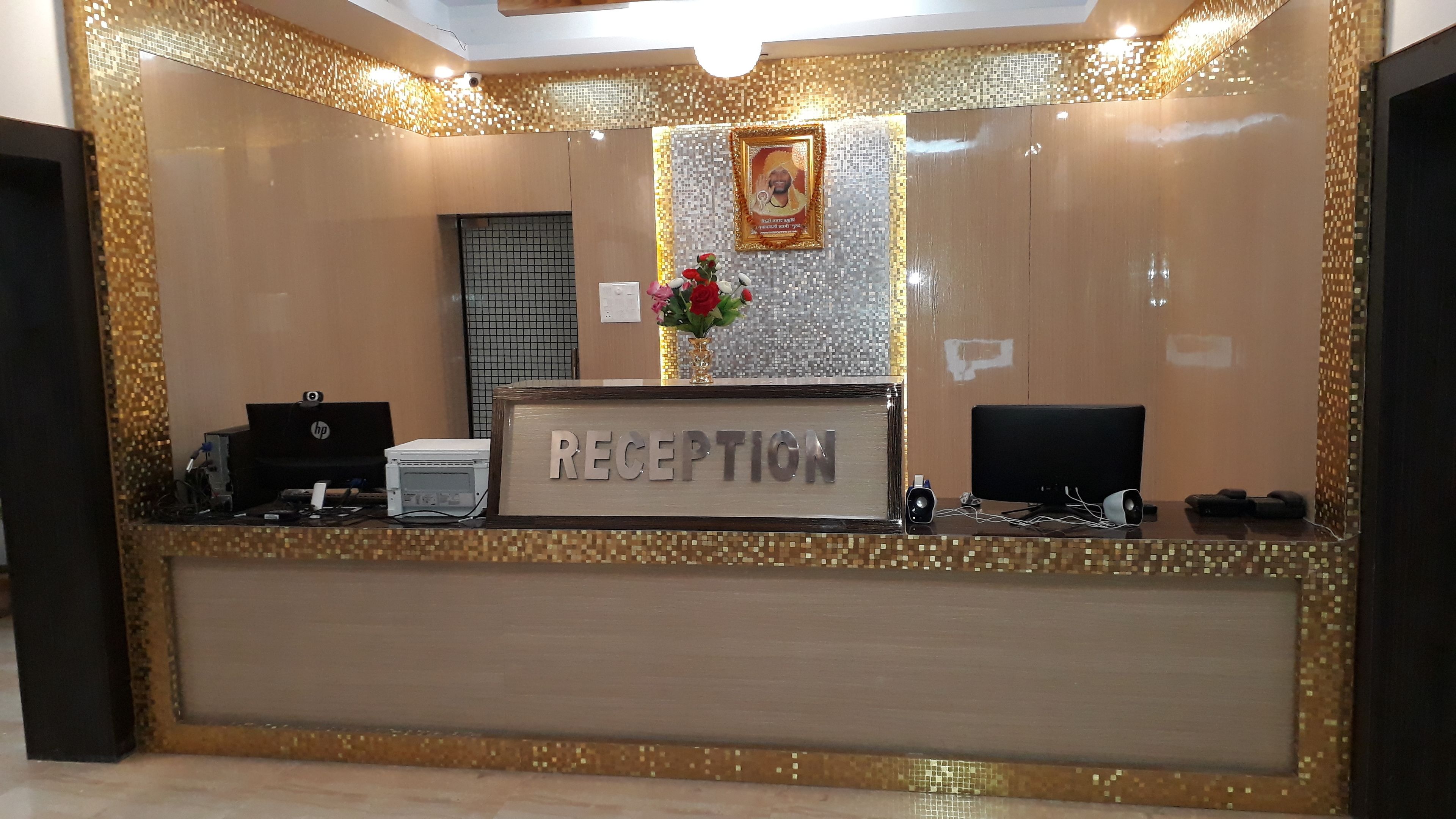 Un mostrador de recepción con un letrero que dice "RECEPTION", un cuadro en la pared y un jarrón con flores.